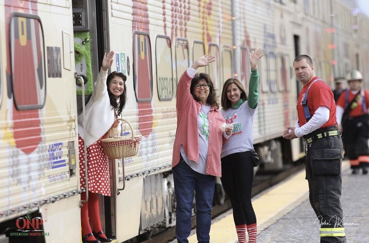 Operation North Pole volunteers waving from the train alongside a firefighter on the platform