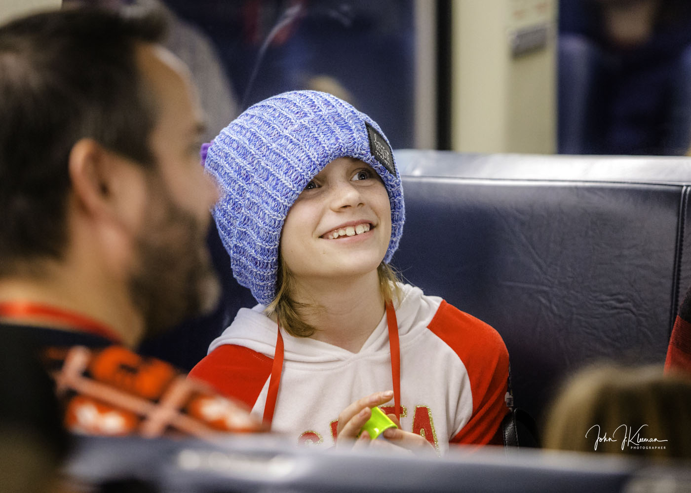 A smiling child in a knit beanie aboard the Operation North Pole train holding a small gift